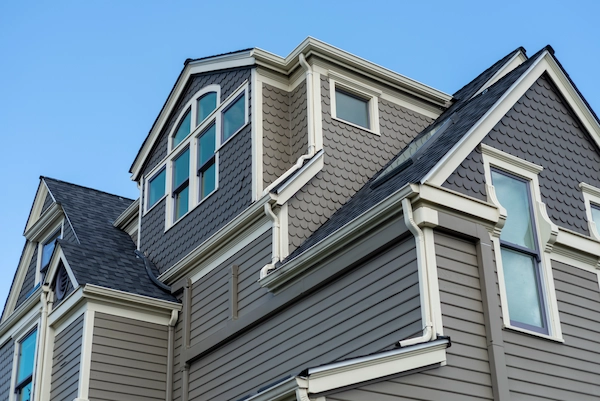 Professional exterior house painting services showcasing gray lap siding, decorative dormer windows, and white trim on a multi-story home